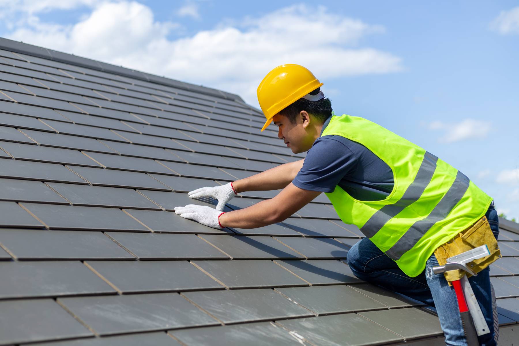 A roofer inspecting a roof for damage